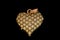 Closeup shot of a sparkly gold heart pendant charm on a black background