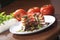 Closeup shot of stacked tomatoes with goat cheese and lettuce salad and vegetables on a table