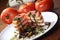 Closeup shot of stacked tomatoes with goat cheese and lettuce salad on a white plate