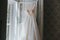 Closeup shot of a stunning white bridal dress hanging in a well-lit room