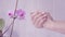 Closeup shot of tender woman hands apply skin cream. light background with violet orchid. Beautiful hands with elegant