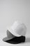 Closeup shot of three blank monochrome white, gray and black baseball cap isolated over light background