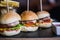 Closeup shot of three mini burgers with french fries and sauce on a wooden tray - food blog concept