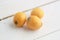 Closeup shot of three small sour mangos isolated on a white wooden surface