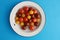 Closeup shot of three types of cherry tomatoes in a bowl on a blue surface