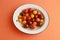 Closeup shot of three types of cherry tomatoes on an orange surface