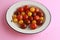 Closeup shot of three types of cherry tomatoes on a pink surface