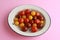 Closeup shot of three types of cherry tomatoes on a pink surface