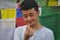 Closeup shot of a Tibetan guy making Korean love sign with his hand, posing against Buddhist prayer flags