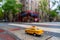 Closeup shot of a toy yellow taxi cab on a pedestrian crossing in a city