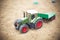 Closeup shot of a tractor toy on the sand in a playground during daytime