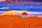 Closeup shot of a transparent sphere in an orange sandy and foamy beach during sunset