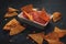 Closeup shot of triangular potato chips dipped in tomato salsa sauce