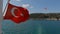 Closeup shot of a Turkey flag flowing on the ship, shining water and harbor in the background