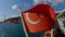 Closeup shot of a Turkey flag flowing on the ship, shining water and harbor in the background