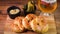 Closeup shot of Turkish buns with beer, pickles, and a sauce on a wooden board
