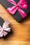 Closeup shot of two black gift boxes with rosy ribbon placed on a brown surface