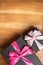 Closeup shot of two black gift boxes with rosy ribbon placed on a brown surface