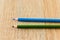 Closeup shot of two blue and green pencils on a wooden surface