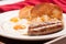 Closeup shot of two eggs with different colored yolks, and sausage and bagel