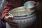 Closeup shot of two silver ritual bowls with a monk performing a Buddhist ritual