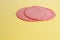 Closeup shot of two slices of salami on a yellow background