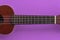 Closeup shot of a ukulele neck on a purple background