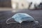 Closeup shot of a used surgical mask on the muddy ground