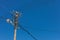 Closeup shot of a utility pole transmission wires under a blue clear sky