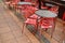 Closeup shot of wet red plastic outside cafe chairs and metal tables after rain