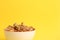 Closeup shot of a white bowl of nuts on a yellow background