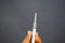 Closeup shot of a white syringe in a person\'s hands behind a dark background