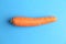 Closeup shot of a whole carrot isolated on a blue background