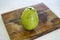 Closeup shot of a whole yummy green pear on a wooden cutting board