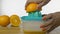 Closeup shot of woman hands squeezing out fresh orange juice on a manual juicer