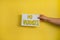 A closeup shot of a woman holding a paper with the word NO VACANCIES on a yellow background