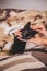 Closeup shot of a woman\'s hand holding a cute young cat on an animal-printed bed cover background