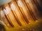 Closeup shot of a wood dipper of honey with studio lights reflecting on it