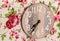 Closeup shot of a wooden clock surrounded by paintings of flowers