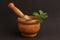 Closeup shot of a wooden herb grinder with a green plant inside on a black background