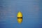 Closeup shot of a yellow buoy on blue water surface