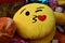 Closeup shot of a yellow round pillow in the shape of the kissing heart emoji