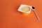 Closeup shot of yogurt and a teaspoon on an orange background
