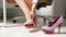 Closeup shot of young woman taking high heels shoes in office