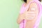 Closeup of shoulder of a vaccinated young Asian girl with adhesive bandage in thumbs up. Young people, children covid vaccination.