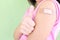 Closeup of shoulder of a vaccinated young Asian girl with adhesive bandage in thumbs up. Young people, children covid vaccination.