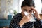 Closeup sick indian woman blowing her nose into paper napkin