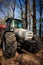 Closeup side view of tractor on big wheels on road in forest