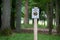 Closeup of a sign with a "closed forest" writing with green trees in the background