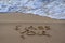 Closeup of a sign I miss you, written on sand. Wave on the beach